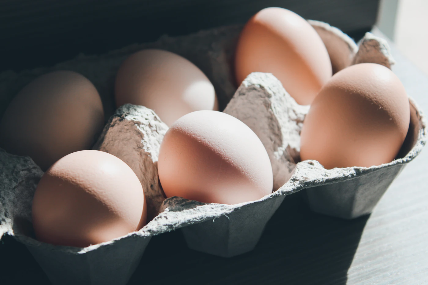 Six fresh brown eggs nestled in a recyclable carton
